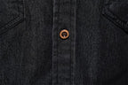Close-up of a dark indigo denim button-up shirt showing the button placket and a single brown button.