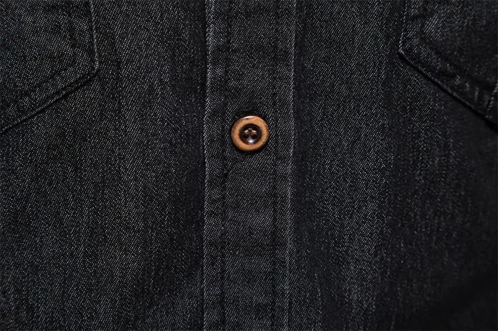 Close-up of a dark indigo denim button-up shirt showing the button placket and a single brown button.